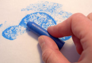 How to make a crayon rubbing: Use the side of the crayon to colour over the shape and make it appear.