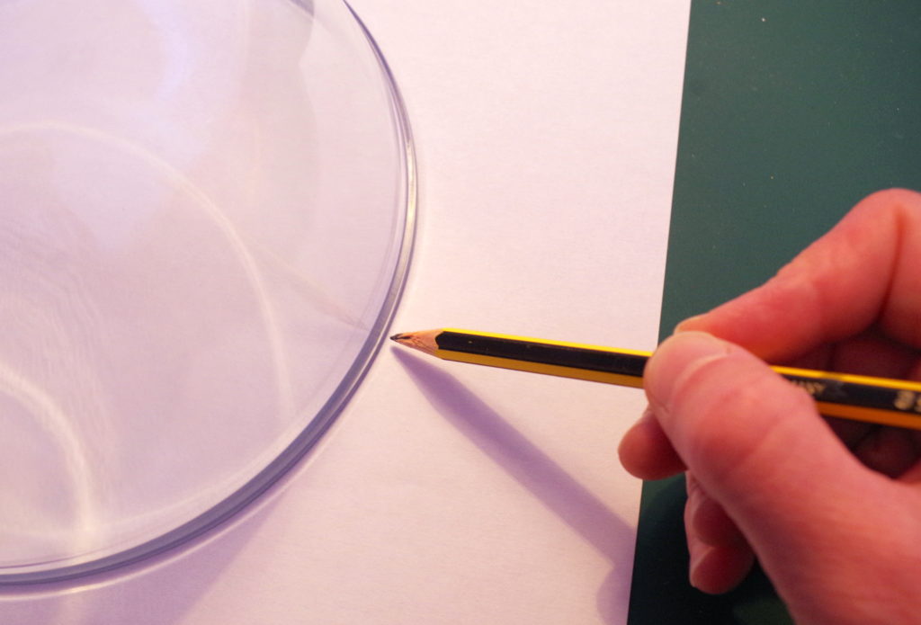 Draw round a bowl to make a large circle on the paper. This will be the outside of the planet.