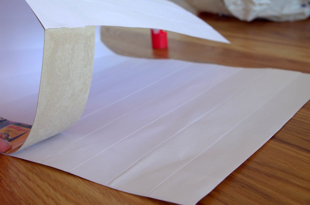 Line up the glued-headband with the bottom edge of the white paper and roll it along, sticking it firmly down as you go.