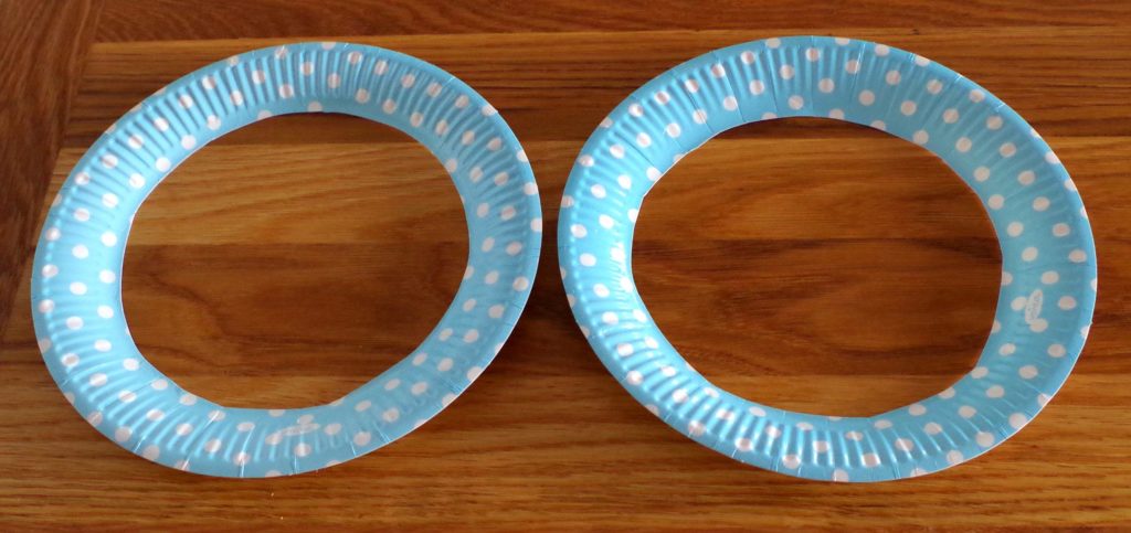 Two paper plates with the centres removed leaving just the rims.