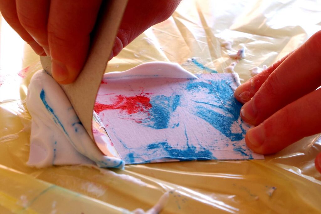 Scrape the excess shaving foam off with a piece of cardboard, leaving marbled card. 